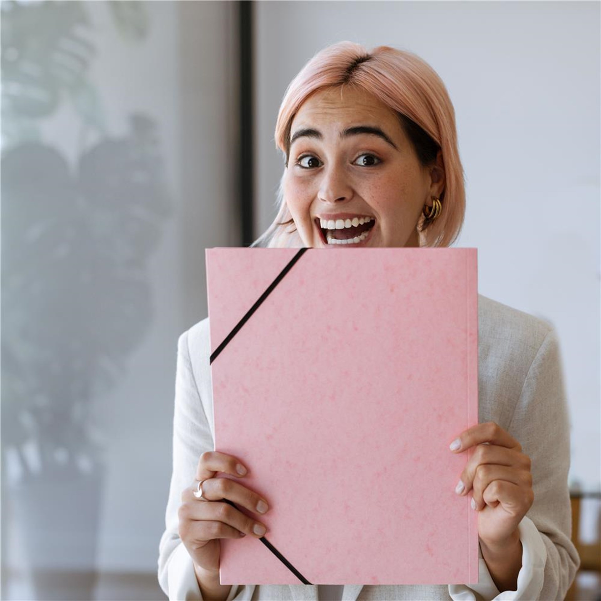 Junge Frau mit rosa gefärbten Haaren hält rosa Bewerbermappe in der Hand