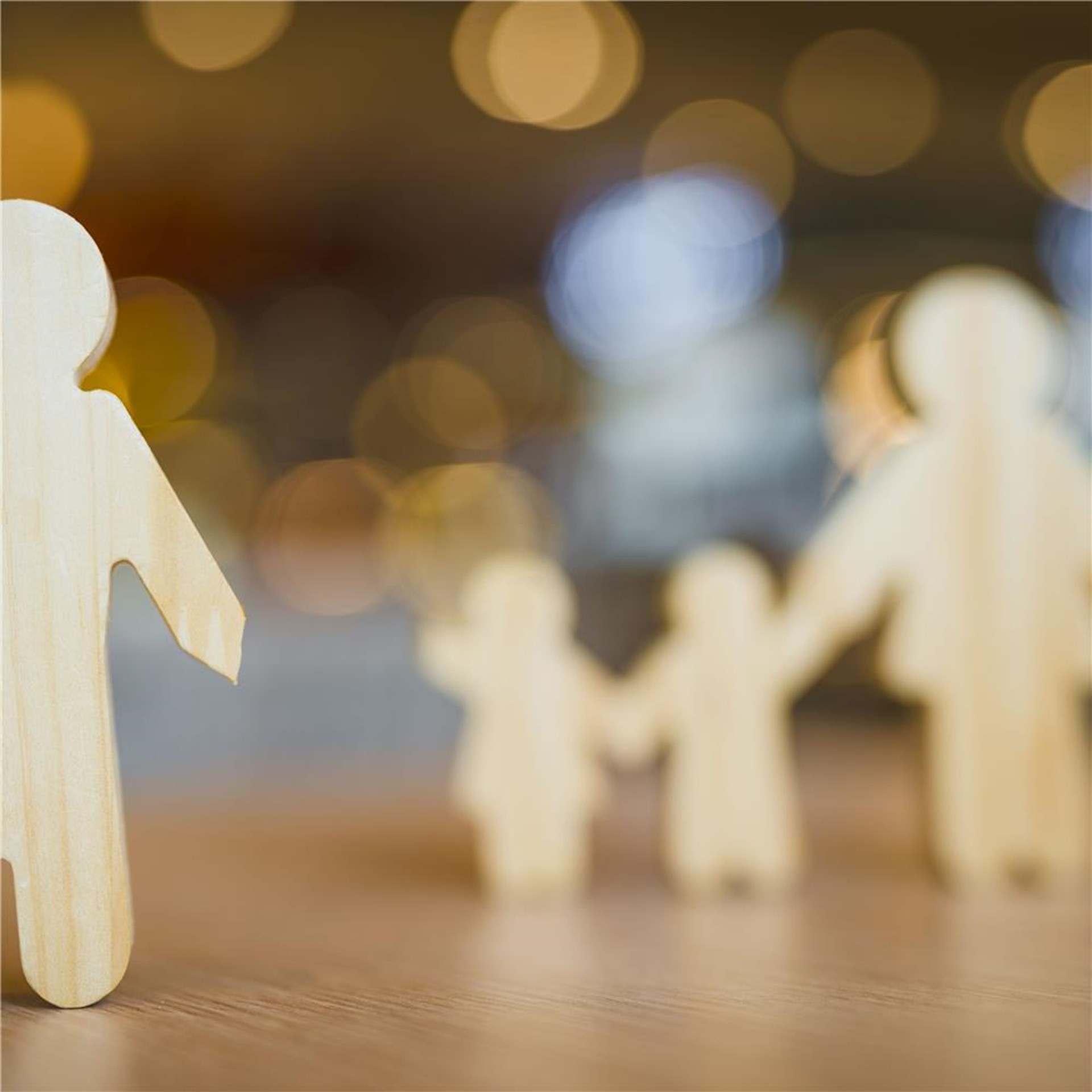Familie aus Holzfiguren, wobei der Vater von Mutter und Kindern entfernt steht